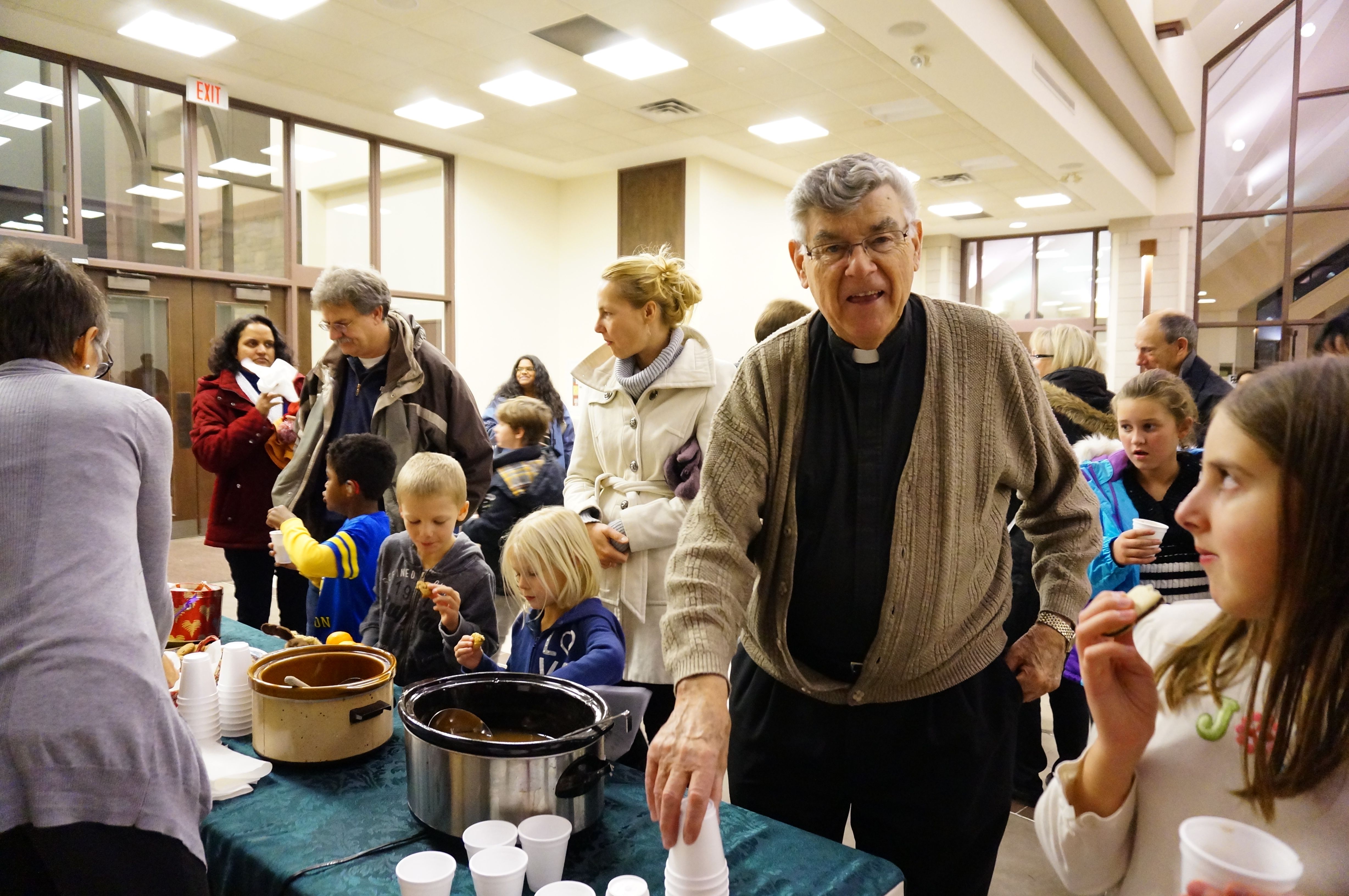 Father Ron Cote helps spread the cheer with a warm beverage and a smile.